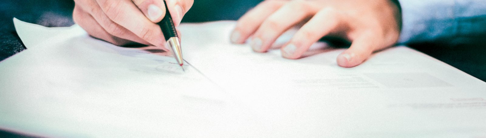 Person filling out documents with a pencil